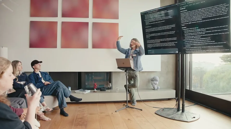 George Pickett presenting at a lectern beside a big screen of code