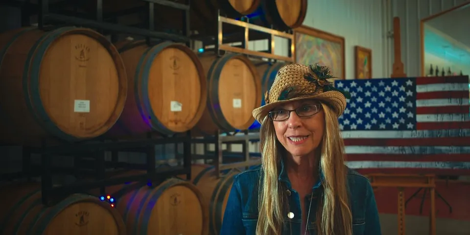 A staff member in a straw hat smiling in the barrel room