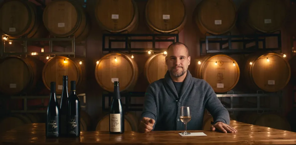 The sommelier seated in the barrel room with a glass and bottles
