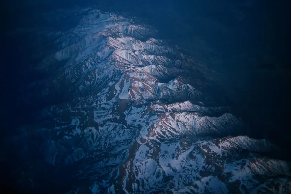 A snowy mountain range from the air at dusk