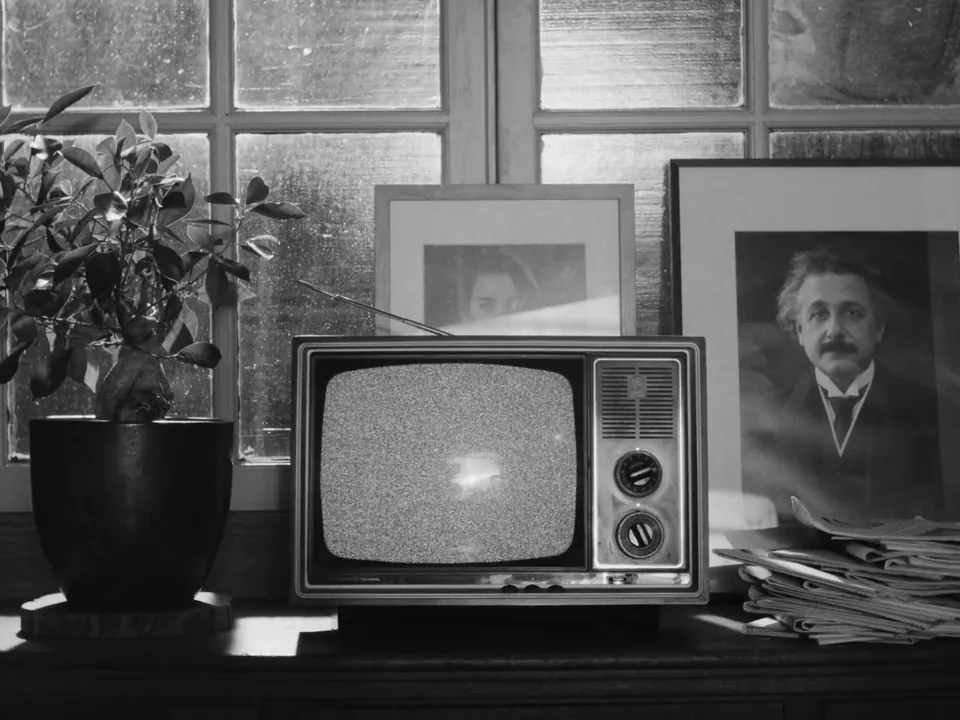 A vintage TV showing static beside a framed portrait of Einstein